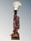A Chinese carved hardwood figural table lamp in the form of a man holding a Koi fish,