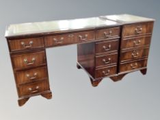 A reproduction mahogany nine drawer twin pedestal desk with tooled leather inset top,