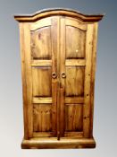 A contemporary stained pine domed top double door wardrobe,