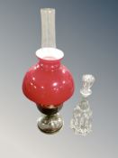 A 20th century oil lamp with red glass shade together with a crystal mallet decanter