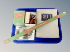 A group of sewing machine accessories, Singer skirt marker rule in original box, Singer sewing book,