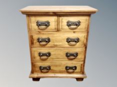 A contemporary stained pine chest of five drawers,