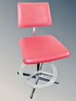 A mid century chrome and red vinyl swivel chair