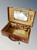 A mid century brown leather cased travelling vanity set with enamelled decoration