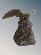 A cast patinated metal sculpture of an eagle on stone plinth,
