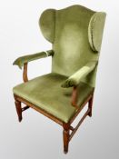 An Edwardian oak wingback armchair in studded green dralon upholstery