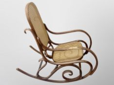 A Thonet-style beech and rattan rocking chair (armrest damaged)