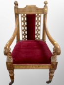 A late Victorian carved oak armchair raised on ceramic castors,