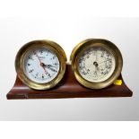 A brass cased quartz timepiece and pressure gauge mounted on mahogany plinth,