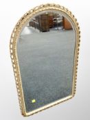 A cream and gilt arch topped bevelled mirror,