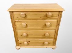 A mid century pine chest of four drawers on bun feet,