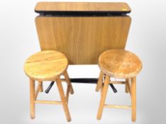 A pair of pine stools and a teak effect drop leaf table