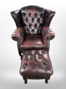 A Chesterfield oxblood button leather wingback armchair with matching footstool