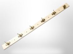 A painted coat rack, with six brass hooks,