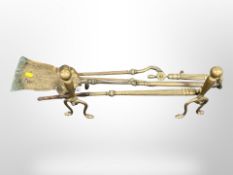 A pair of brass fire dogs and three companion pieces