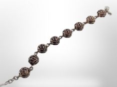 A silver bracelet decorated with stylized roses,