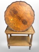 A figured walnut circular low table on claw and ball feet together with an oak two tier trolley