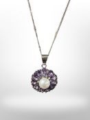 A silver pendant set with a pearl within a border of violet coloured stones on silver chain