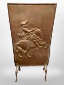A copper fire screen depicting a man on horseback,