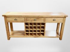 A contemporary solid oak dresser base fitted three drawers and wine rack,