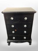 An ebonised five drawer chest with glass handles,
