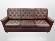 A late 20th century Danish brown buttoned leather three piece suite comprising of three seater