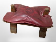 A brass mounted camel stool with leather cushion