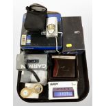 An Olympus digital camera together with Garmin sport's watch, digital alarm clock,