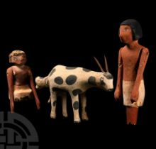 Egyptian Painted Wooden Model of a Cow Giving Birth, Together with Two Figures