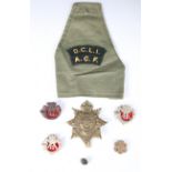 A collection of various Duke of Cornwall's Light Infantry badges and buttons, including a helmet