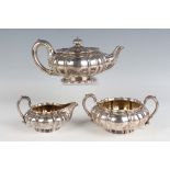 A William IV and later silver three-piece tea set of squat circular lobed form, crest engraved,