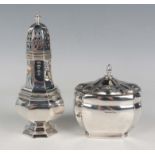 A silver tea caddy of oval form with canted sides beneath a similarly decorated domed hinged lid,