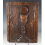 A 17th century walnut ecclesiastical panel, carved in relief with a communion chalice and wafer,