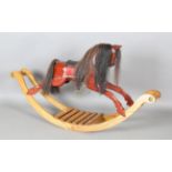 A modern carved wooden rocking horse, raised on an ash base, height 77cm, length 143cm.Buyer’s