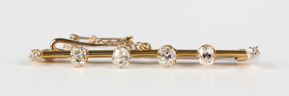 An Edwardian gold and diamond six stone bar brooch, claw set with a row of cushion cut diamonds