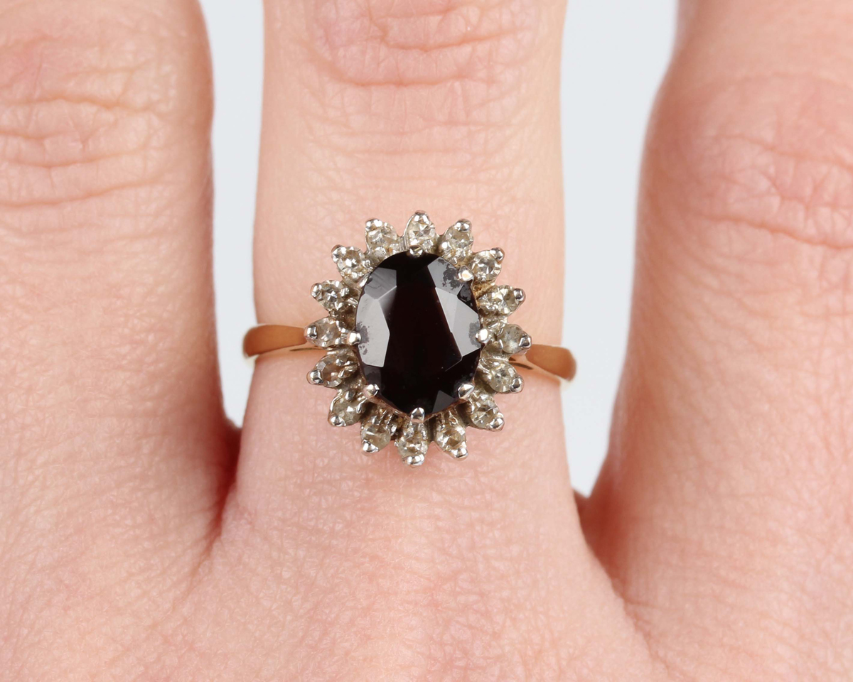 A gold, garnet and diamond cluster ring, claw set with an oval cut garnet within a surround of - Image 2 of 5