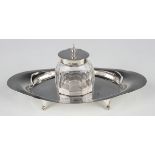 An Edwardian silver and cut glass inkstand, the central facet cut oval inkwell with silver collar