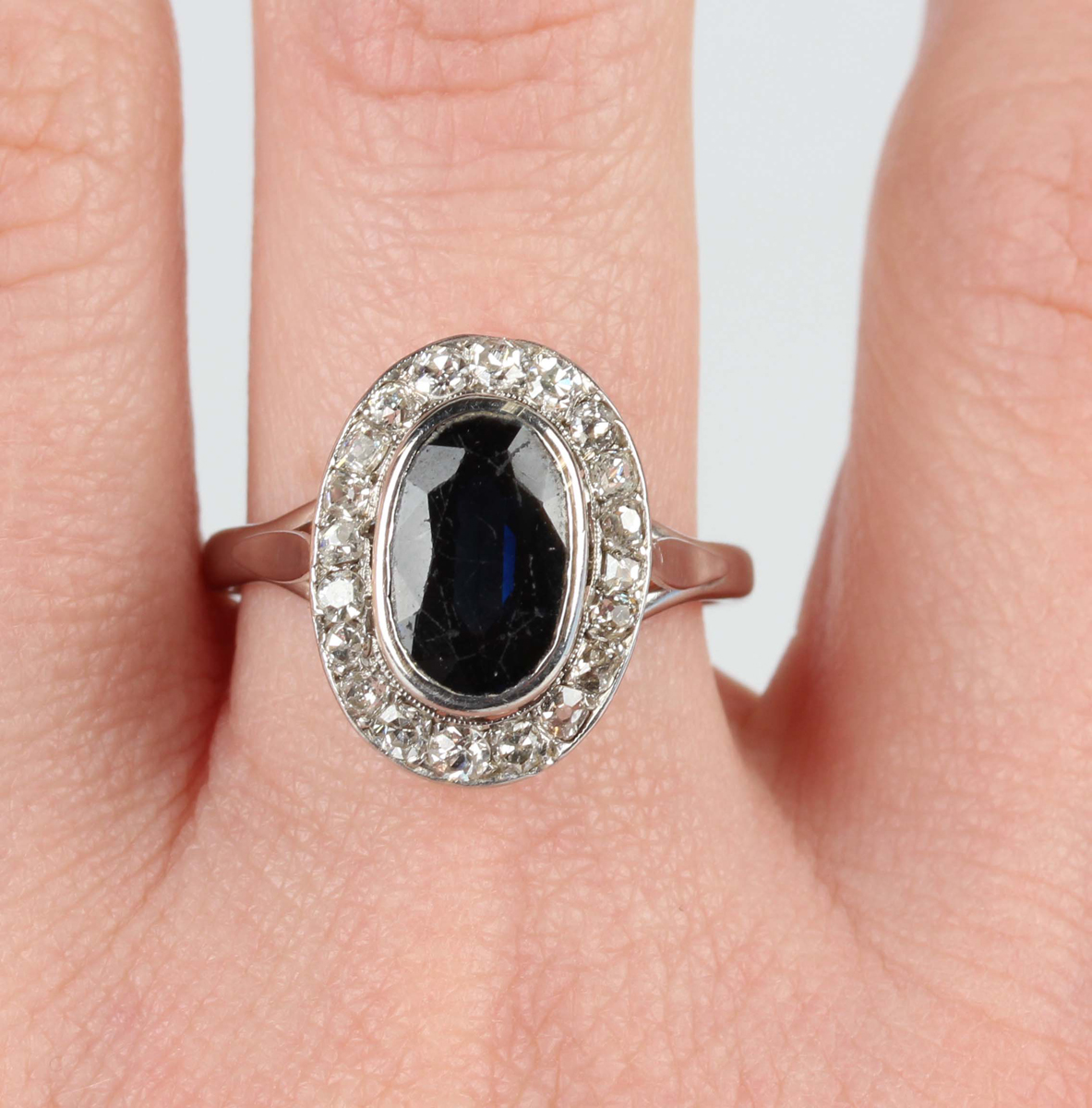 A white gold, sapphire and diamond oval cluster ring, collet set with an oval cut sapphire within - Image 2 of 5