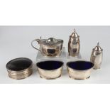 A silver five-piece condiment set of oval form with reeded rims, comprising two pepper casters,