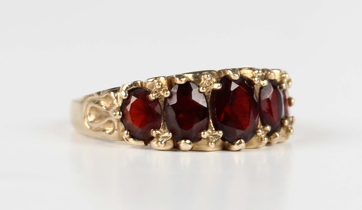 A 9ct gold and garnet five stone ring, claw set with a row of oval cut garnets graduating in size to