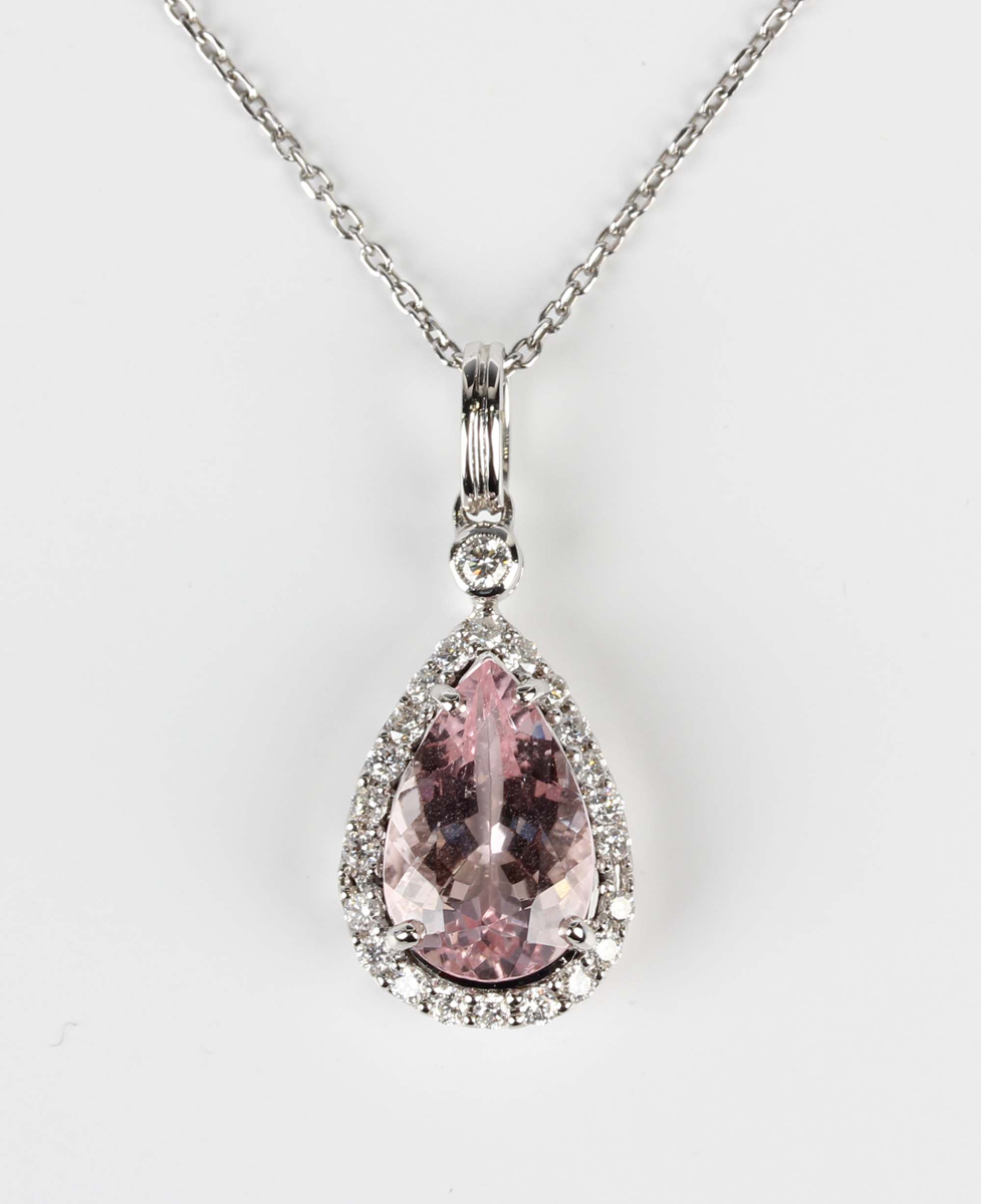A white gold, morganite and diamond cluster pendant, claw set with a pear shaped morganite within