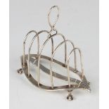 A late Victorian silver four-division toast rack with loop handle, raised on claw and ball feet,