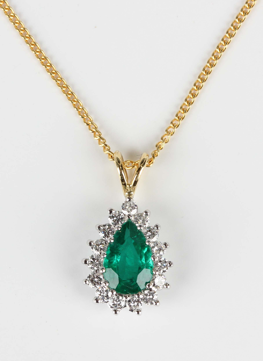 An 18ct two colour gold, emerald and diamond cluster pendant, claw set with a pear shaped emerald