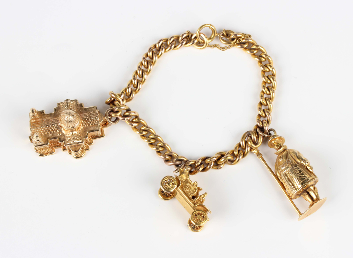 A 9ct gold curblink charm bracelet on a boltring clasp, fitted with three 9ct gold charms,