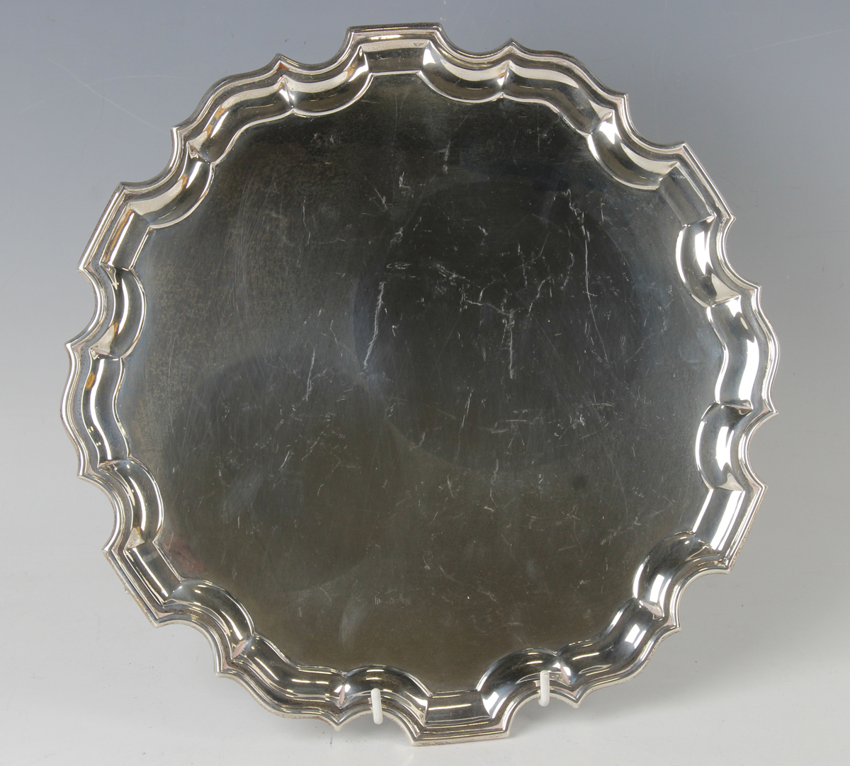 A George V silver circular salver with raised piecrust rim, on scroll feet, Sheffield 1911 by Jay,