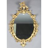A George III Rococo period giltwood oval wall mirror, the frame carved with overall flowers and