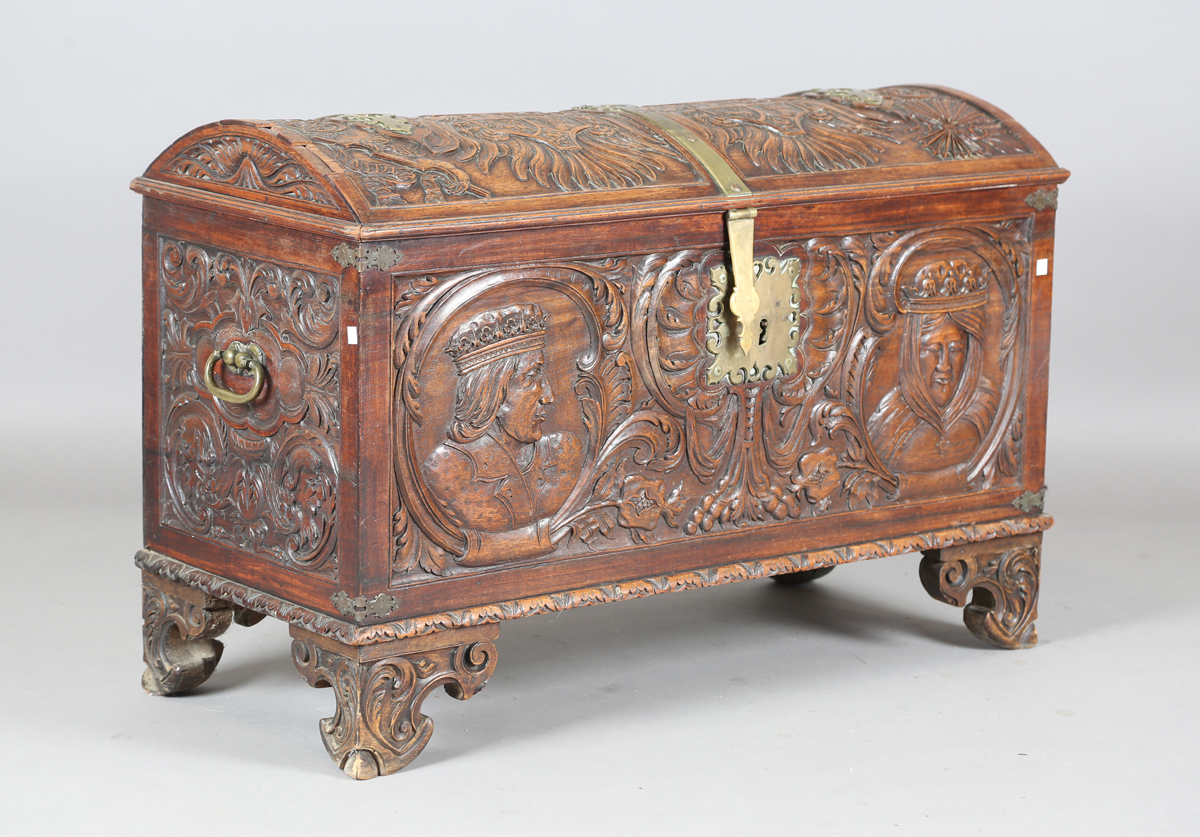 An 18th century French walnut domed trunk, finely carved with coats of arms, initials and further