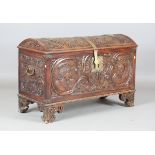 An 18th century French walnut domed trunk, finely carved with coats of arms, initials and further