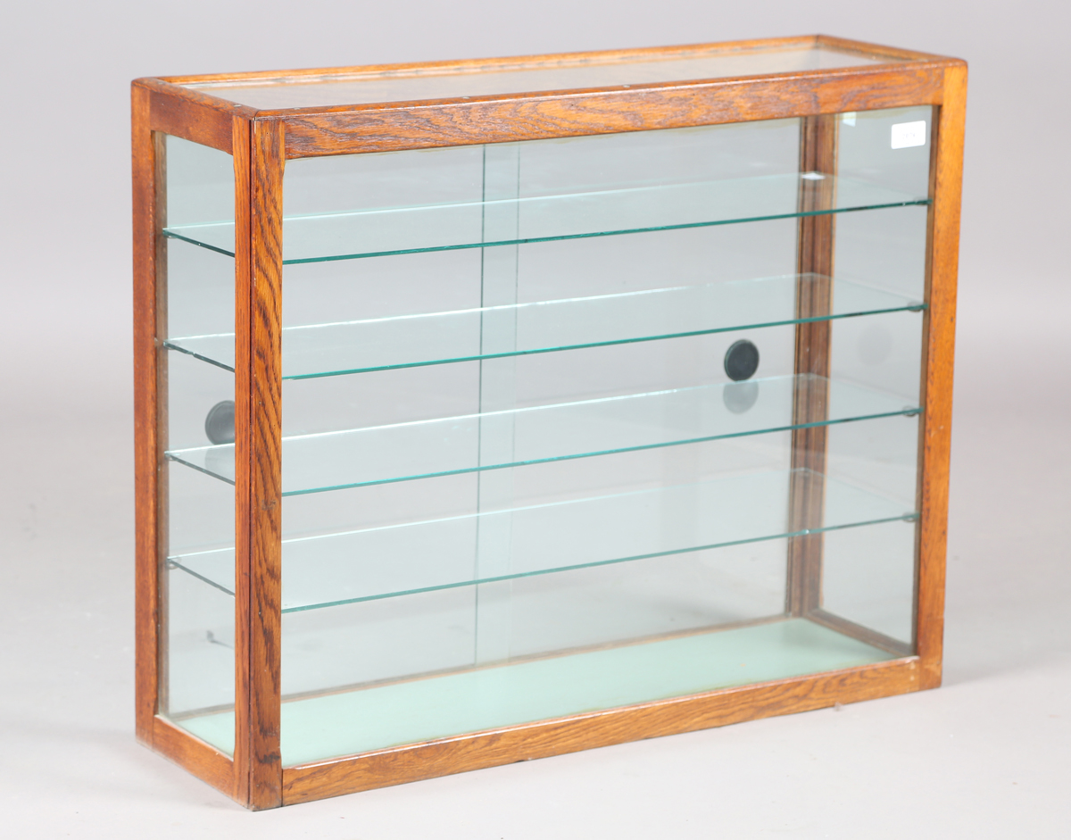 An early 20th century oak framed counter-top display cabinet, fitted with glass shelves and