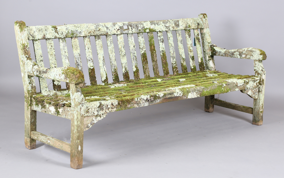 A 20th century teak garden bench, covered in green lichen, height 81cm, width 182cm, depth 70cm.